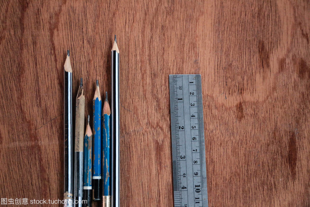 照片有一顶视图的铅笔和钢直尺放在木制板作为背景使用